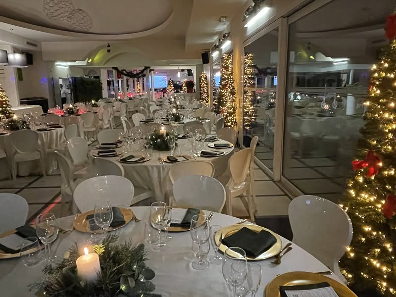 Tavoli apparecchiati e alberi illuminati per il Natale nella sala di Villa ReNoir