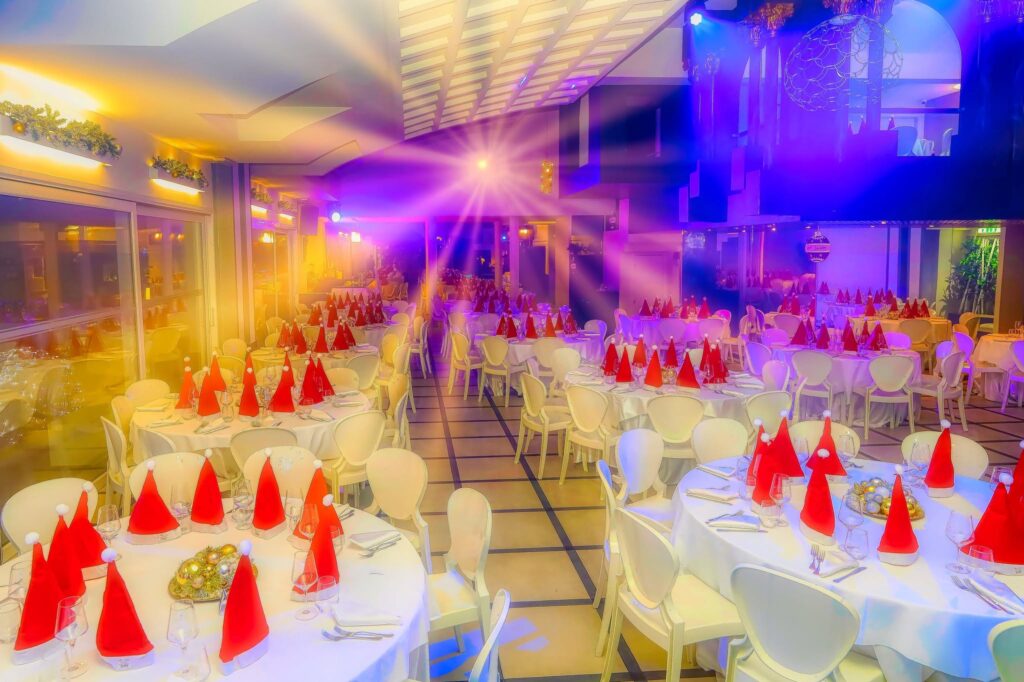 Sala di Villa ReNoir con tavoli apparecchiati, tovaglioli rossi e luci per eventi